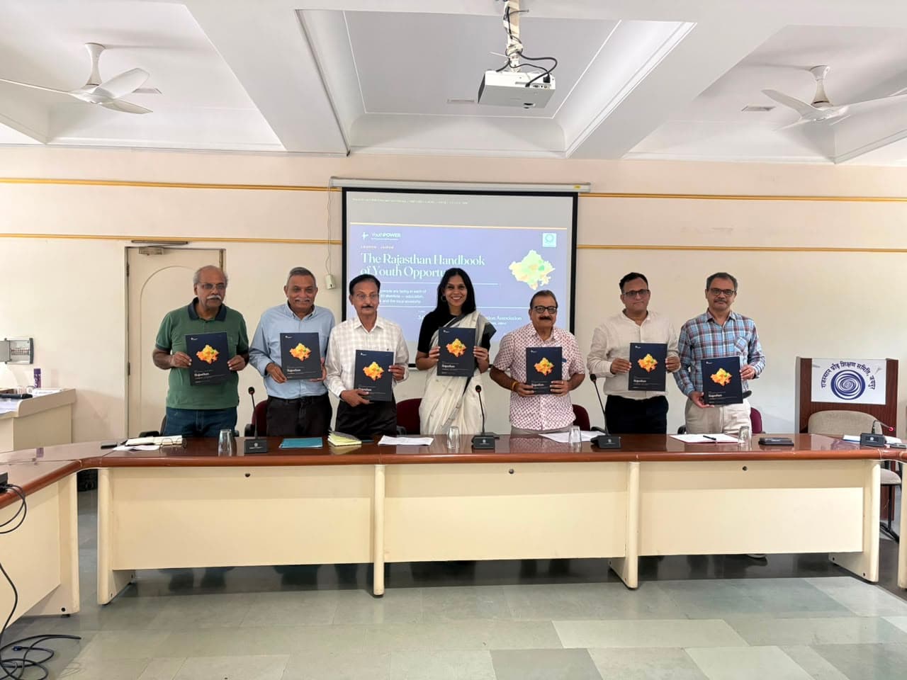 Launch participants holding copies of the Rajasthan Handbook of Youth Opportunity at the front of the meeting room.