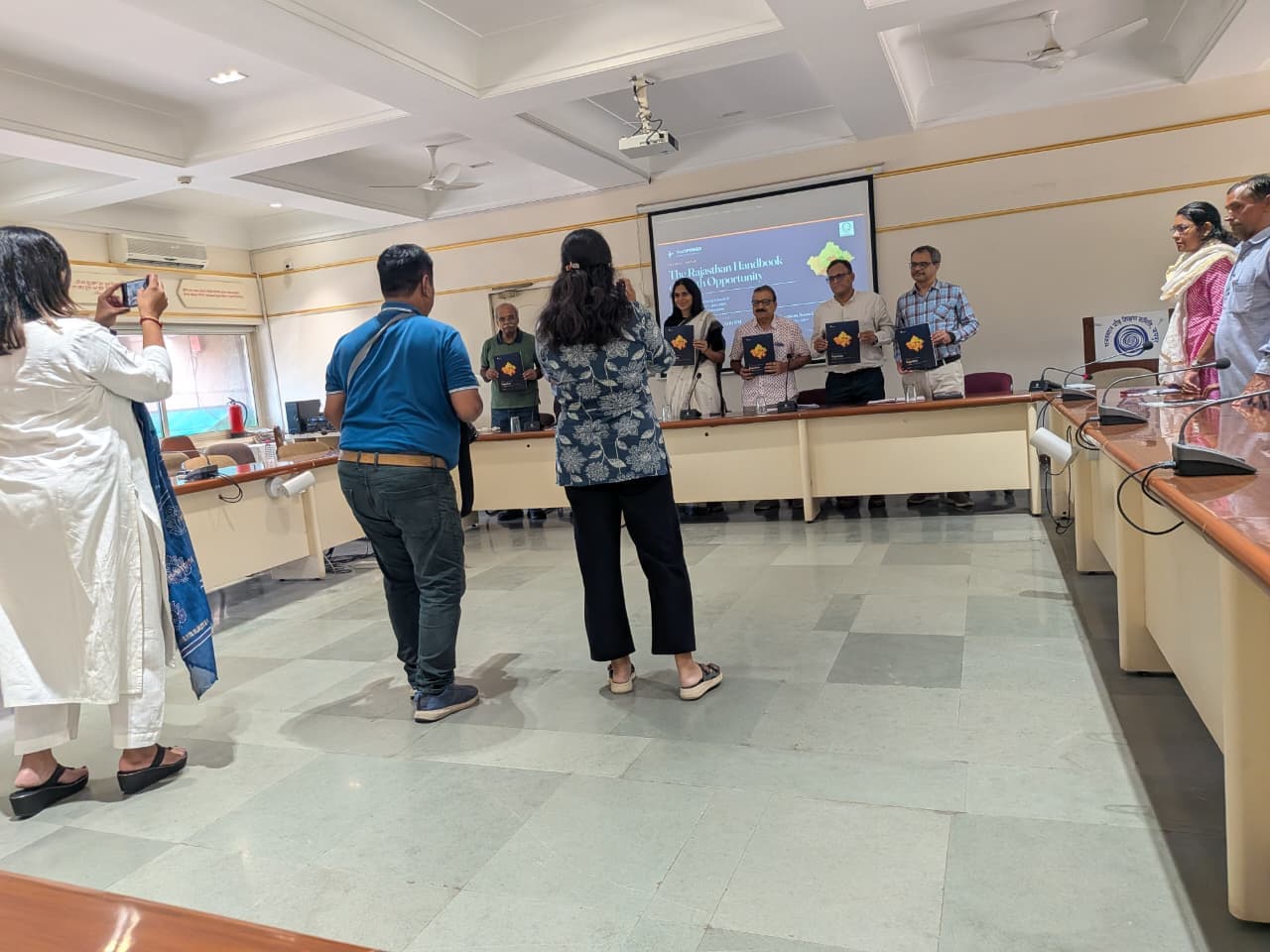 Attendees photograph the presentation of the Rajasthan youth opportunity handbook.
